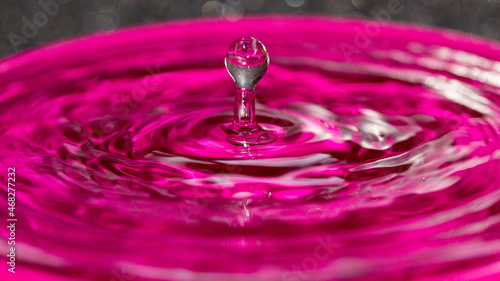 Frozen in time a pink water splash column attached to a sphere on top - stock photo
