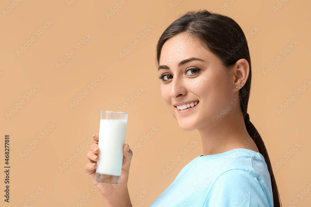 Young woman with glass of organic milk on color background