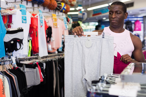 African male customer choosing sportswear in sporting goods store