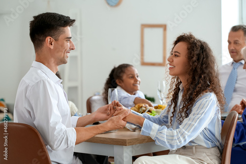 Thanksgiving Day. Smiling happy couple having dinner with their family at served table