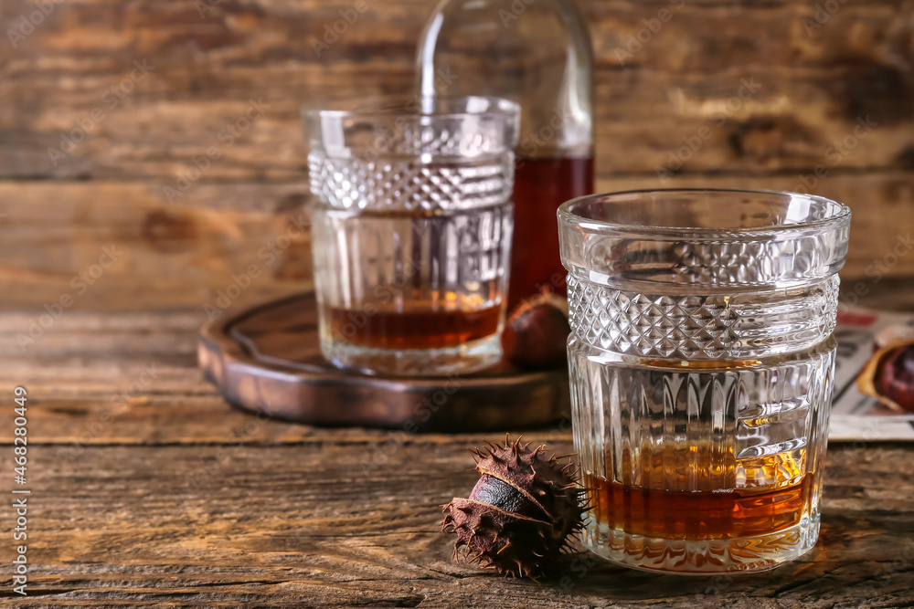 Fototapeta premium Glasses of chestnut whiskey on wooden background