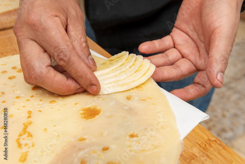 Chef's hands placing banana slices inside a sweet crepe he is preparing