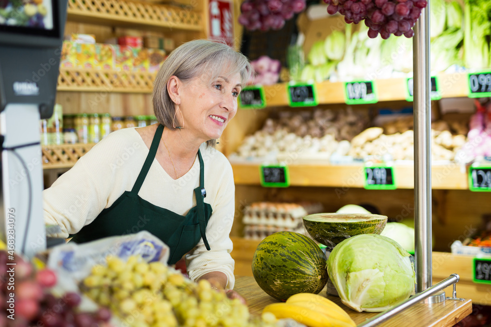 Senior caucasian woman seller standing at counter in greengrocer.