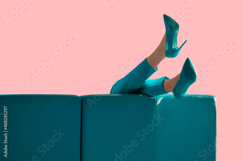 Women's feet in turquoise shoes on the sofa.