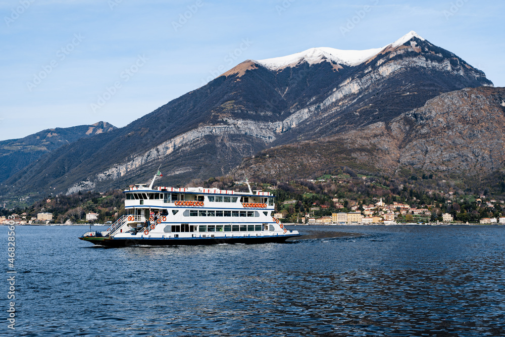 Ferry floats against the backdrop of snow-capped mountains. Lake Como, Italy