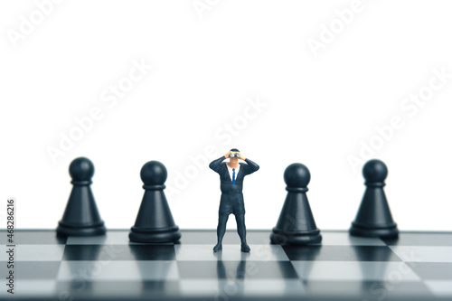 Businessman using binoculars standing in beetween chess pawn. Miniature tiny people toys photography. isolated on white background.
