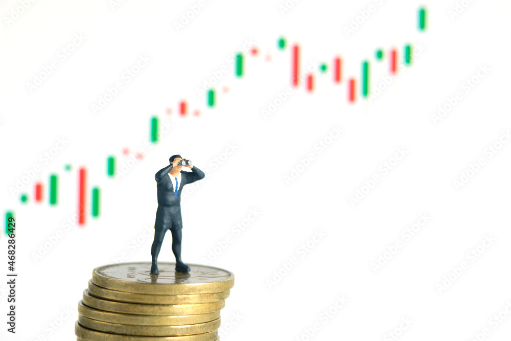 Businessman using binoculars standing above coin stack, with bullish growth increase candle stick chart. Miniature tiny people toys photography. Businessman using binoculars standing above coin stack, with bullish growth increase candle stick chart. Miniature tiny people toys photography.
