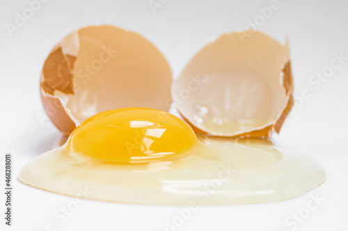 сырое куриное яйцо рядом со скорлупой  на белом фоне, вид сверху