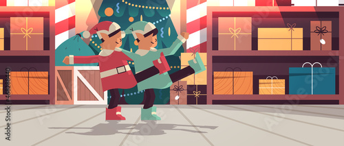 elves in uniform having fun santa helpers couple celebrating happy new year merry christmas holidays workshop interior