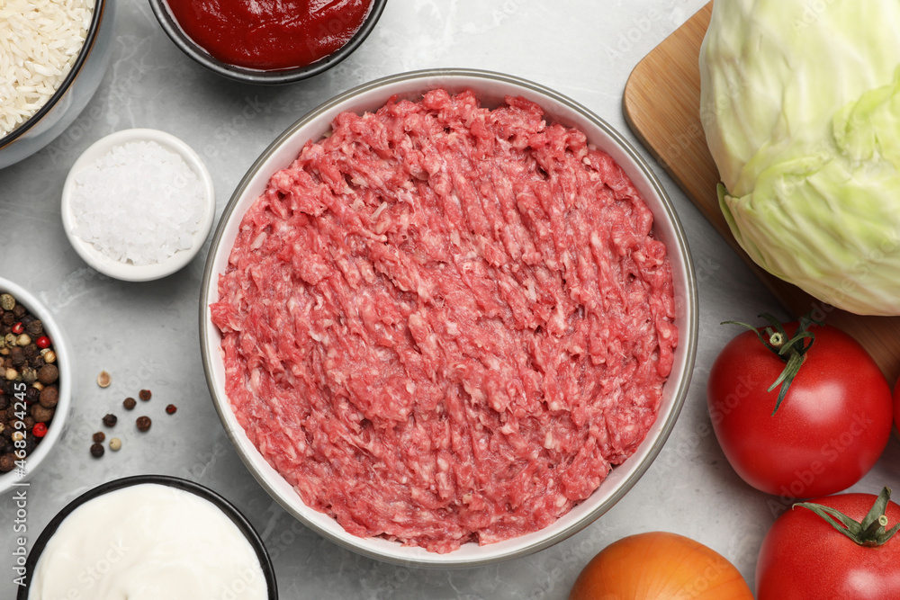 Minced meat in bowl and other ingredients for stuffed cabbage rolls on light grey table, flat lay Minced meat in bowl and other ingredients for stuffed cabbage rolls on light grey table, flat lay