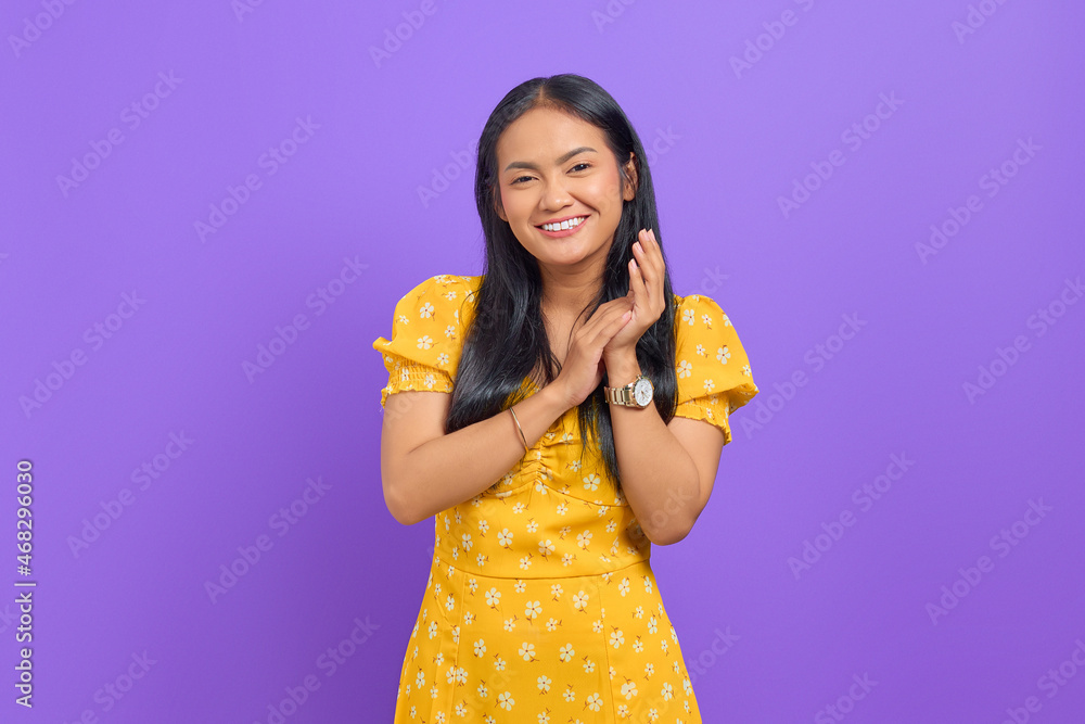 Smiling young Asian woman rub hands and looking at camera on purple background Smiling young Asian woman rub hands and looking at camera on purple background