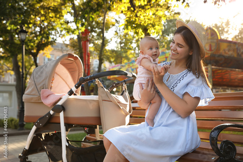 Happy mother with baby sitting on bench in park
