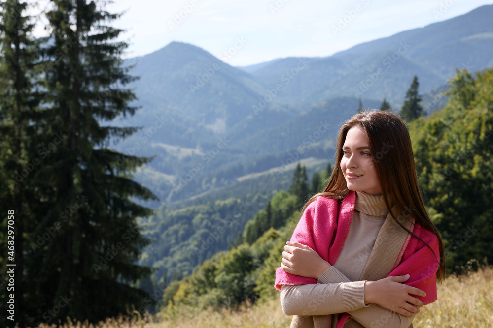 Young woman in mountains on sunny day, space for text