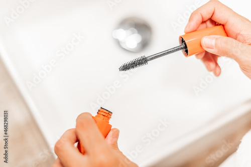 Hands of a woman holding eyelash brush.
