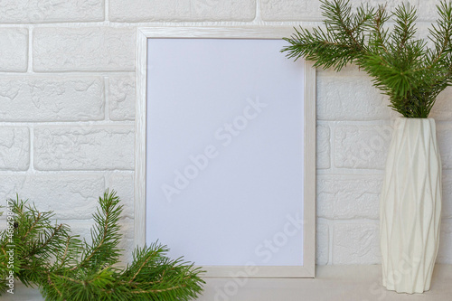 Christmas mockup of wooden photo frame on white brick wall background. Mockup with a Christmas tree branch