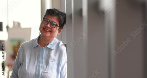 Positive mature Asian female smiling for camera at home