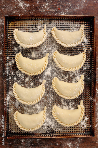 View from above of baking tray with raw empanadas for cooking. Traditional South American food.