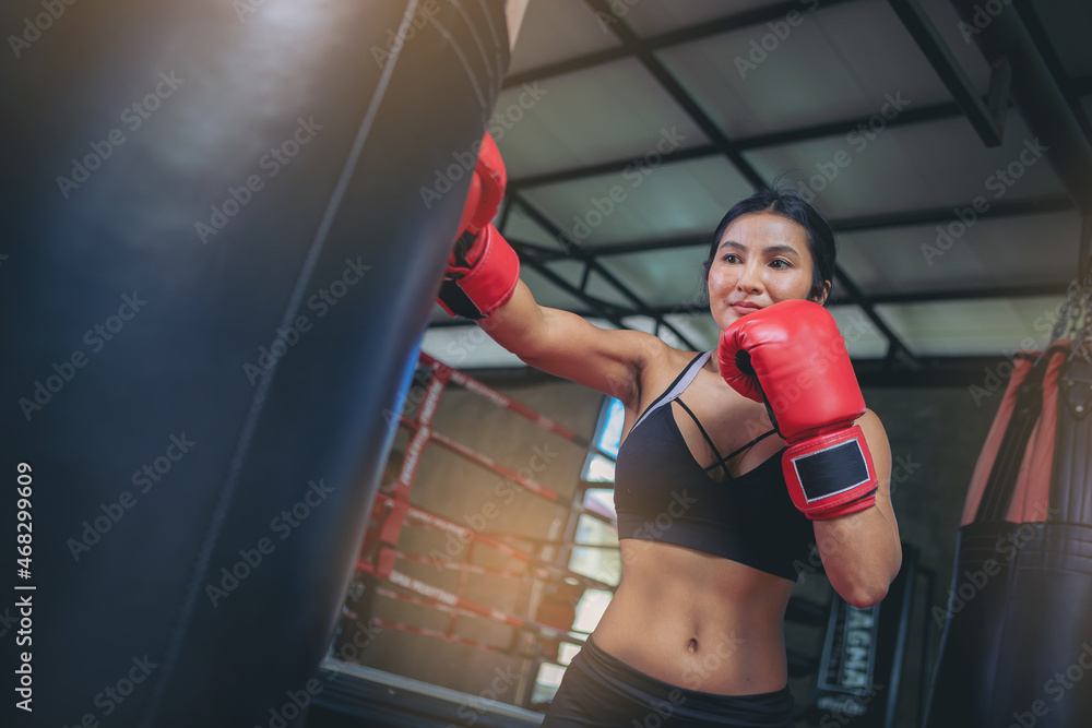 Asian sexy woman doing workout exercise by boxing with sandbag at fitness gym. Selected focus	