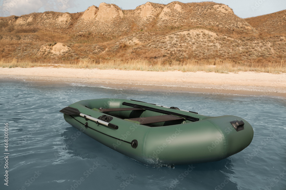 Inflatable rubber fishing boat floating in sea near coast Inflatable rubber fishing boat floating in sea near coast