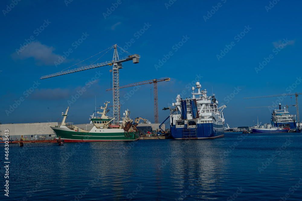 Ships moored at the marina in a fishing port while tourist walk nearby, taken in Skagen on 30. Oct..