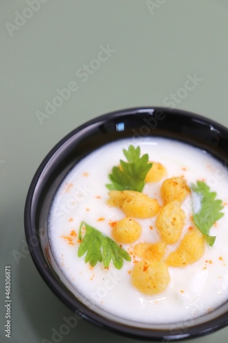 Boondi Raita or Dahi Bundi rayta is a Popular condiment from Rajasthan, India. Served with coriander toppings in a bowl over the flat background. copy space. Yogurt dip.  photo