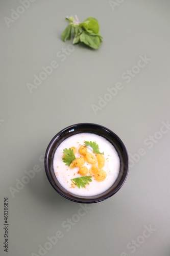 Boondi Raita or Dahi Bundi rayta is a Popular condiment from Rajasthan, India. Served with coriander toppings in a bowl over the flat background. copy space. Yogurt dip.  photo