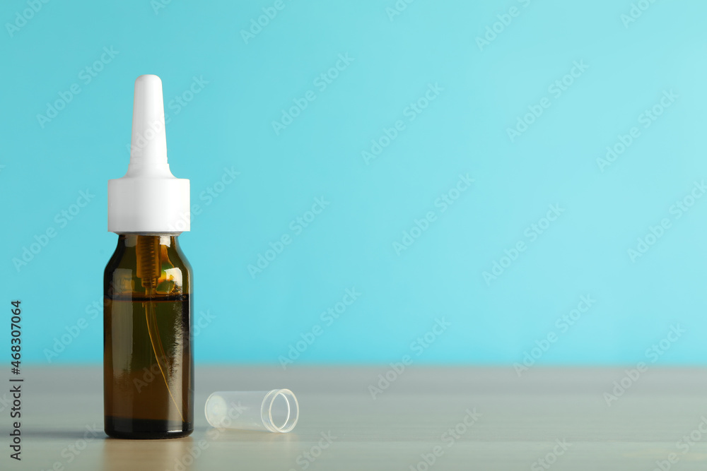 Bottle of nasal spray on table against light blue background, space for text Bottle of nasal spray on table against light blue background, space for text