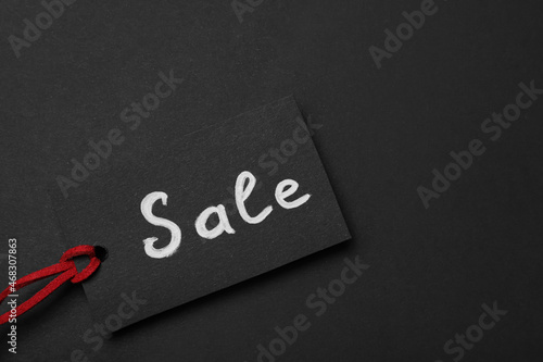 Tag with word Sale on dark background, top view and space for text. Black Friday