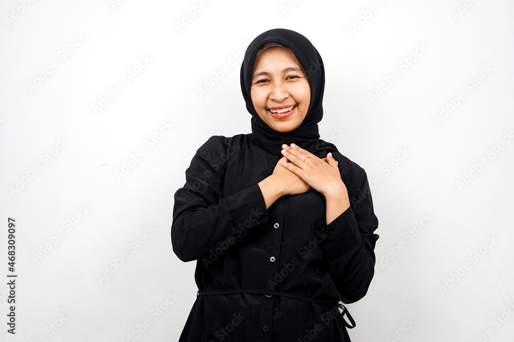 Beautiful and cheerful young asian muslim woman, with hands holding chest, isolated on white background Beautiful and cheerful young asian muslim woman, with hands holding chest, isolated on white background
