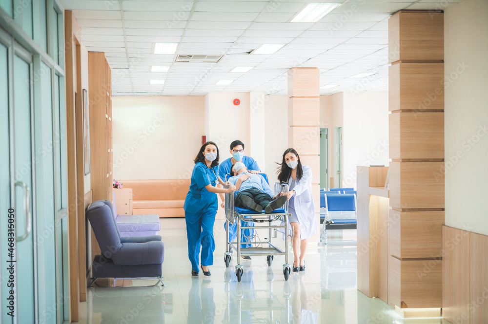 Emergency Department staff push Gurney with Seriously heart attacked patient towards the Operating Room. Bright Modern Hospital with Professional Staff Saving Lives.