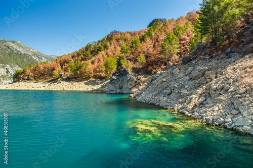 Panorama landscape of reservoir with blue transparent water and mountains with rocks and stones.