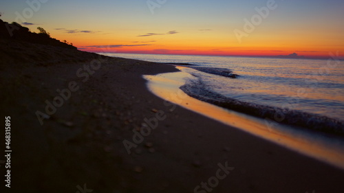 Panorama view peaceful seashore with mountain silhouette at golden sunrise