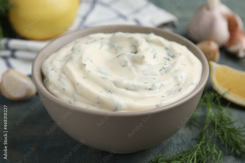 Tasty creamy dill sauce in bowl on blue wooden table, closeup Tasty creamy dill sauce in bowl on blue wooden table, closeup