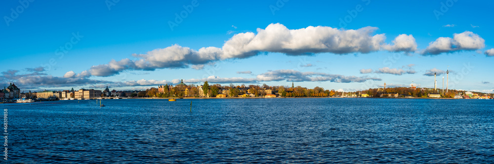 Beautiful autumn panorama of Stockholm, the capital of Sweden on sunny day. The islands of Djurgården and Skeppsholmen. An embankment with old architecture buildings, palaces and attractions park.