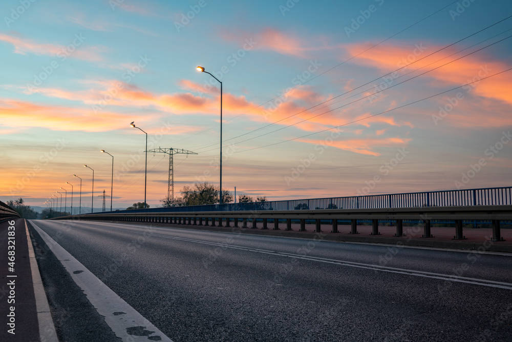 Asphalt road leading a bridge during the beautiful sunrise
