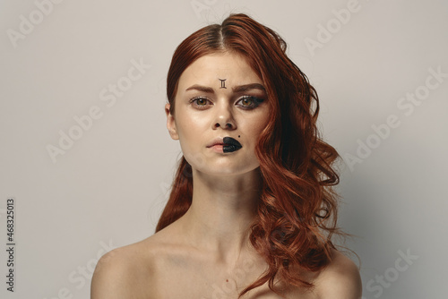 pretty woman with zodiac sign on her face red hair close-up