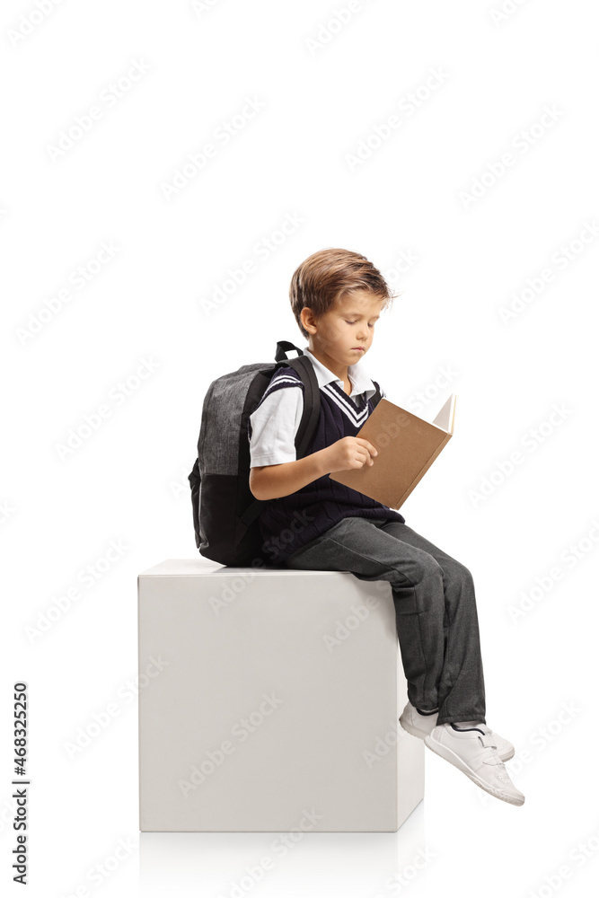 Schoolboy sitting on a white cube and reading a book Schoolboy sitting on a white cube and reading a book