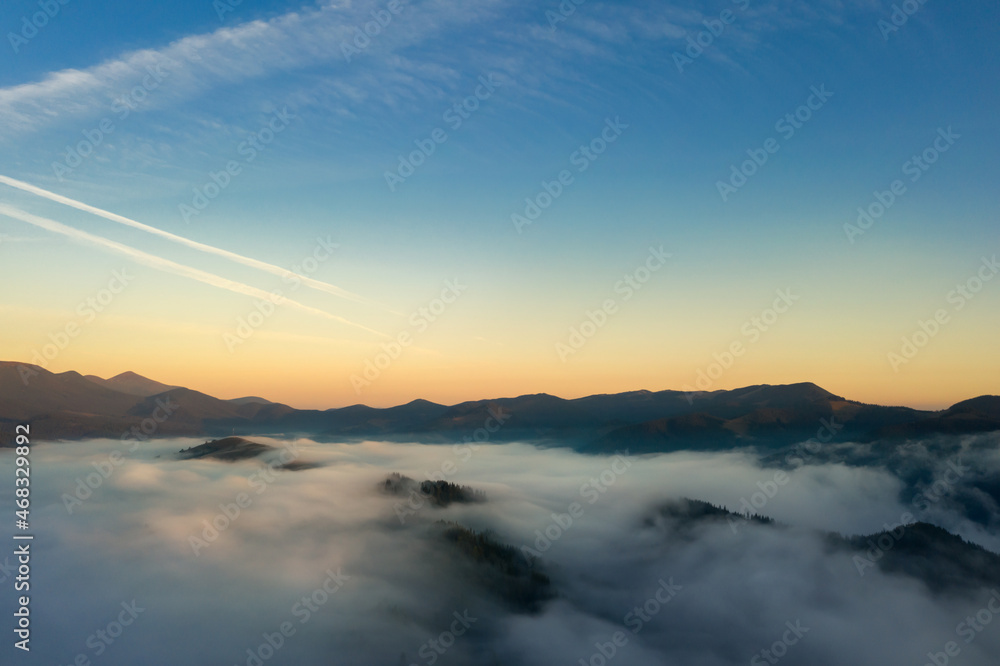 Aerial view of beautiful mountains covered with fluffy clouds in morning. Drone photography