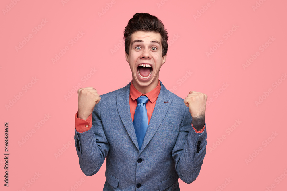 Cheerful businessman celebrating success with clenched fists - obrazy, fototapety, plakaty 