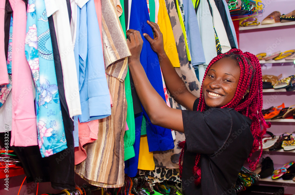 beautiful young african woman smiling as she is shopping for clothes in store