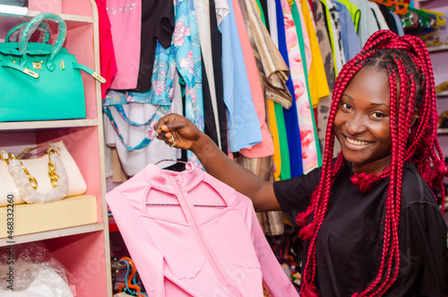 beautiful young african woman smiling as she is shopping for clothes in store