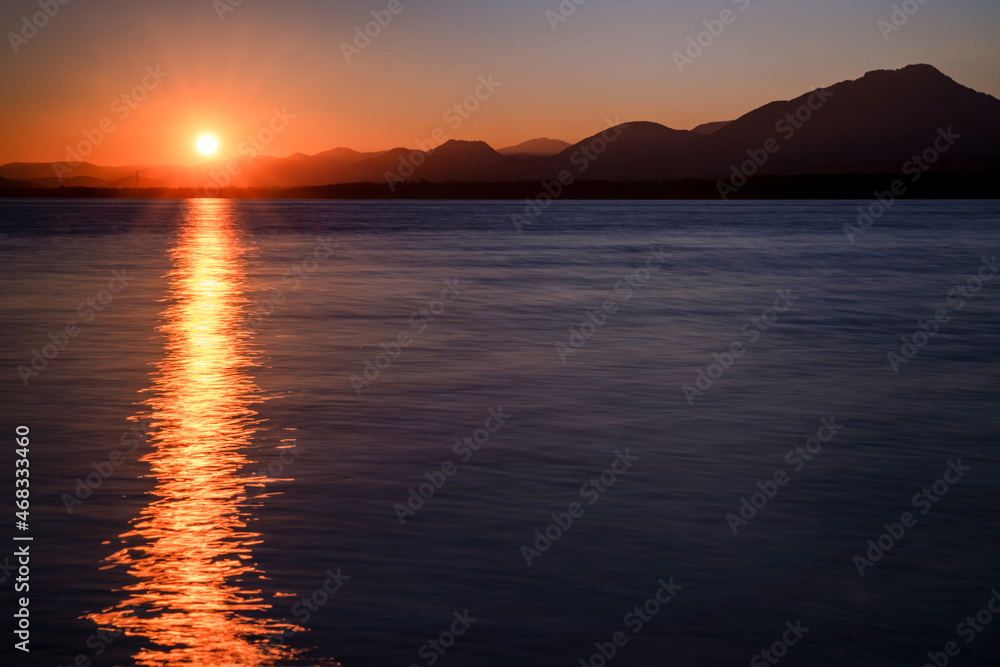 Reflecton of sunrays on water surface during beautiful sunrise