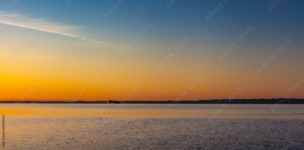 Summer landscape with river and sky illuminated by the rising sun