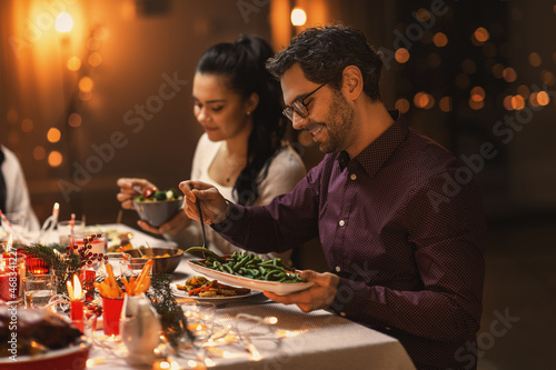 holidays, party and celebration concept - happy friends having christmas dinner at home