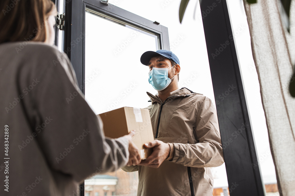 health protection, safety and pandemic concept - delivery man in face protective mask giving parcel box to female customer at home health protection, safety and pandemic concept - delivery man in face protective mask giving parcel box to female customer at home