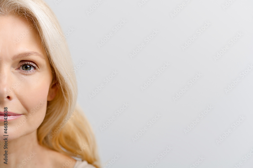 Half-face portrait of elegant beautiful middle-aged woman, gorgeous and bright mature lady looks at the camera with serious face, pure skin with fine wrinkles. Face and body care, anti aging care Half-face portrait of elegant beautiful middle-aged woman, gorgeous and bright mature lady looks at the camera with serious face, pure skin with fine wrinkles. Face and body care, anti aging care