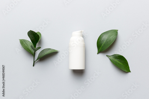 Organic cosmetic product with green leaves on color background. Flat lay