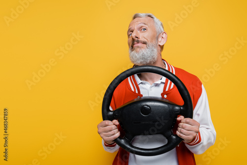 Fotografie, Tablou pleased middle aged man in bomber jacket holding steering wheel while imitating