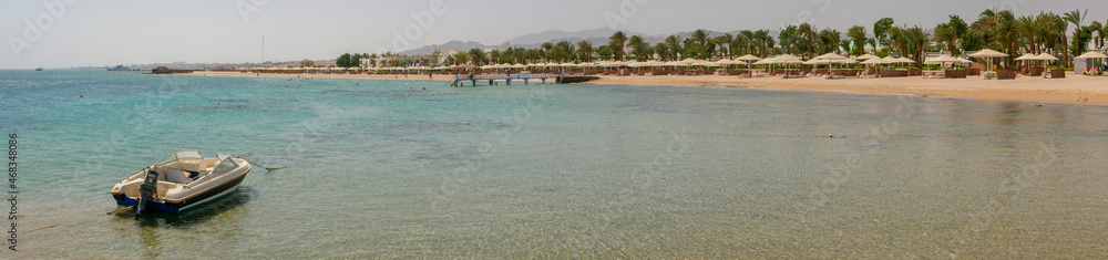 Hurghada, Egypt - September 22, 2021: Panoramic view from the motor boat and the coast of the red sea. People are relaxing and swimming on the sandy beach. Hurghada, Egypt - September 22, 2021: Panoramic view from the motor boat and the coast of the red sea. People are relaxing and swimming on the sandy beach.