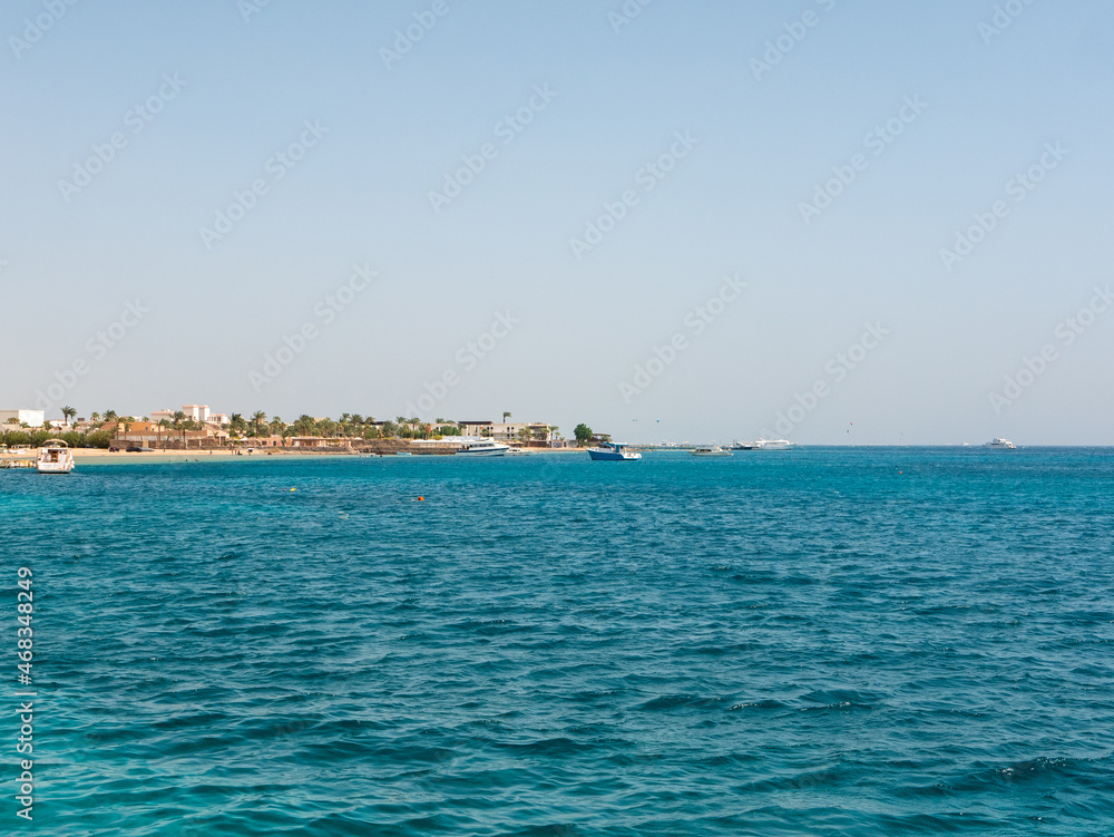 Hurghada, Egypt - September 22, 2021: View of the azure water of the Red Sea and the sandy Egyptian beach. Boats and yachts stand near the shore. Copy space.